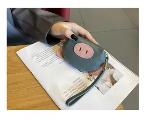 Detailed view of cute leather mini coin purse with pig design and wrist strap, fashion style.