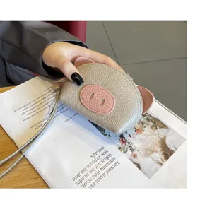 Detailed view of cute pig coin purse made of genuine leather in grey with pink details and wrist strap.