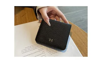 Detailed view of the black genuine leather short wallet, minimalist compact design with metal clasp.