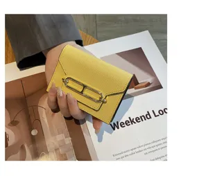 Detailed view of the yellow leather card holder with metal clasp, elegant and chic texture.