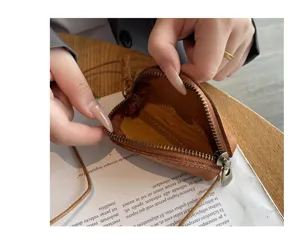 Detail view of mini genuine leather coin purse with zipper and neck strap, brown color.