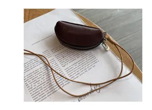 Close-up detail of the mini leather coin purse showing the smooth zipper and hanging lanyard.