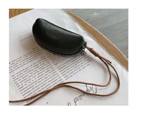 Close-up view of mini dark green genuine leather coin pouch with long brown lanyard.