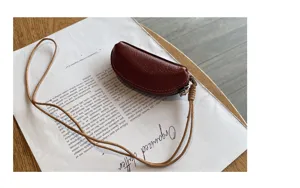 Genuine leather mini coin purse with lanyard detail view showing texture and zipper closure.