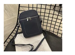 Mini leather phone bag detail view, showing front zipper pocket, silver hardware and strap.