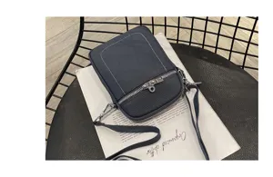 Detailed close-up view of dark blue leather mini phone shoulder bag with front zipper.