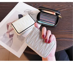 Close-up detail of compact multi-slot zippered leather card holder with quilted texture.