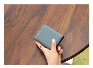 Primer plano de una mini cartera tarjetero azul grisácea minimalista con ranuras en acordeón.