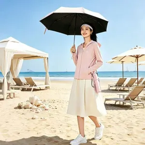 Parasol anti-UV compact à trois pliages avec étui portable dans un décor de plage.