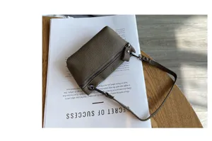 Detail view of mini genuine leather coin purse with zipper and short handle on modern background.