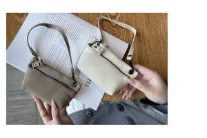 Close-up detail of mini genuine leather coin purses in dual colors with zipper and wrist strap.