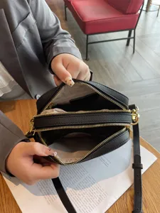 Black genuine leather camera crossbody bag with double zipper compartments and adjustable strap.