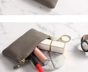 Grey genuine leather coin purse detail showing zipper, puller and keychain design.