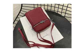 Red leather mini phone bag detail shot, compact crossbody purse with zipper pocket and strap.