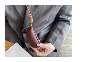 Detail view of mini genuine leather coin purse with lanyard, soft brown texture close-up.