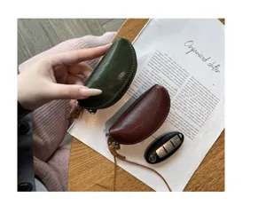 Detailed view of genuine leather half-moon coin purse and key pouch with strap on wooden desk.
