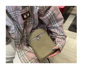 Detailed shot of a minimalist khaki leather crossbody phone bag, showcasing fine texture and zipper.