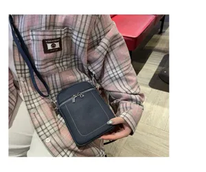 Detail view of the mini genuine leather phone bag in dark blue, featuring metal zippers and strap.