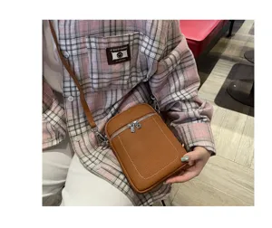 Close-up detail of a brown leather mini crossbody phone bag featuring silver hardware.