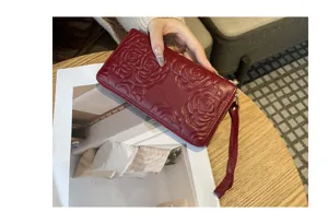 Red genuine leather long zip wallet with elegant embossed floral pattern and strap.