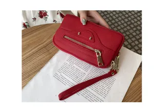 Red genuine leather clutch bag detail, stylish motorcycle design with metal studs and zipper.