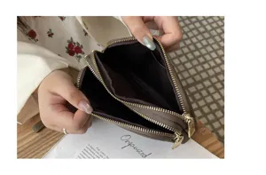 Close-up view showing the spacious interior compartments and double zippers of the leather pouch.