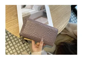 Embossed camellia leather long wallet detail shot, elegant purple zipper purse craftsmanship.
