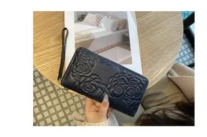 Closeup of dark blue genuine leather long wallet featuring elegant embossed camellia flower design.
