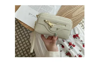 Detailed shot of the white leather motorcycle clutch bag featuring double zippers and wrist strap.