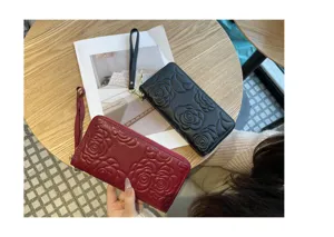 Exquisite embossed floral texture detail on the black and red leather zipper wallet.
