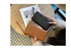 Genuine leather long wallet with camellia embossed design, zipper closure and wrist strap.