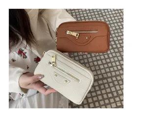 Genuine leather motorcycle clutch bag detail showing brown and white color options with dual zippers.