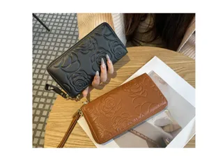 Long leather wallet with embossed camellia flower design, zip around closure and wrist strap.