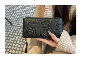Black genuine leather long wallet for women with elegant camellia embossed zip design.