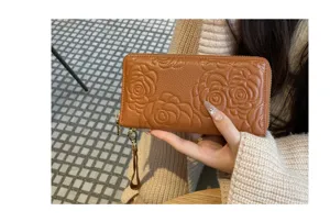 Detailed view of brown leather long wallet featuring elegant embossed camellia flower design.