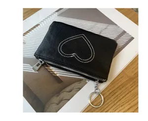 Detailed view of black leather coin purse with white heart stitch pattern and metal zip pull.