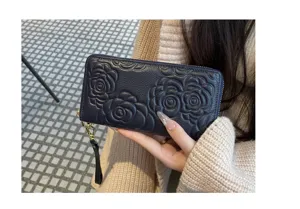 Detail view of a genuine leather long wallet featuring elegant embossed camellia flowers.