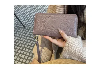 Detailed view of women genuine leather long wallet featuring embossed camellia floral pattern.