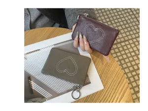 Detail view of compact genuine leather coin purse with heart stitching and keyring.
