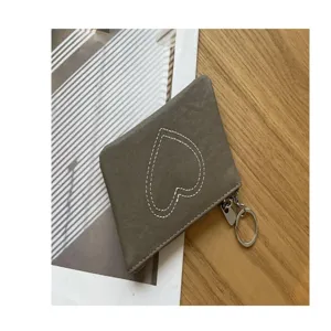 Compact grey leather coin purse detail shot featuring heart stitch pattern and metal keyring.