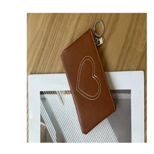 Detail shot of a brown leather coin purse featuring cute heart stitching and a handy keyring.