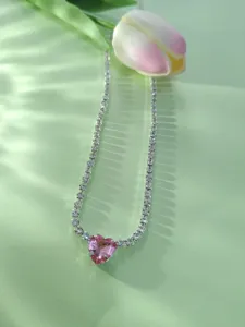 Gros plan d'un magnifique collier ras du cou tennis en cristal cœur rose avec des strass scintillants.