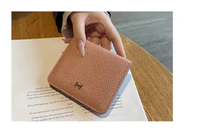 Close-up detail view of the pink leather short wallet with metal H clasp and soft texture.