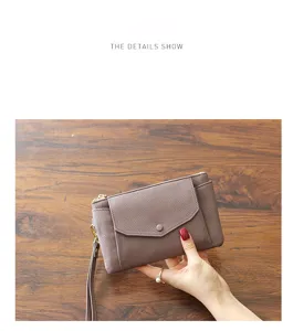 Detailed view of the women's greyish purple leather clutch purse with wrist strap.