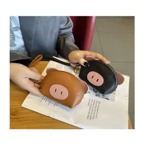 Closeup detail of cute mini leather pig coin purse with wristlet strap in brown and black.