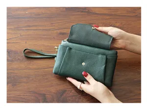 Detail view of dark green leather clutch wallet showing interior structure and wrist strap