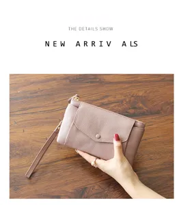 Detailed view of women's leather clutch wallet with wrist strap and snap button close.