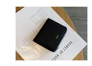Black genuine leather short wallet with metal H clasp compact card holder detailed view.