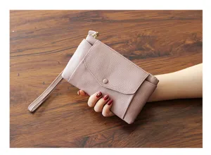 Close-up view of minimalist genuine leather clutch detail, featuring wrist strap and pocket.
