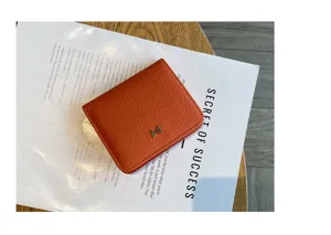 Detailed view of orange leather compact short wallet featuring a metal H clasp design.